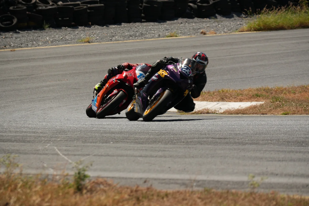 Dos pilotos de motociclismo inclinando sus motocicletas en una curva