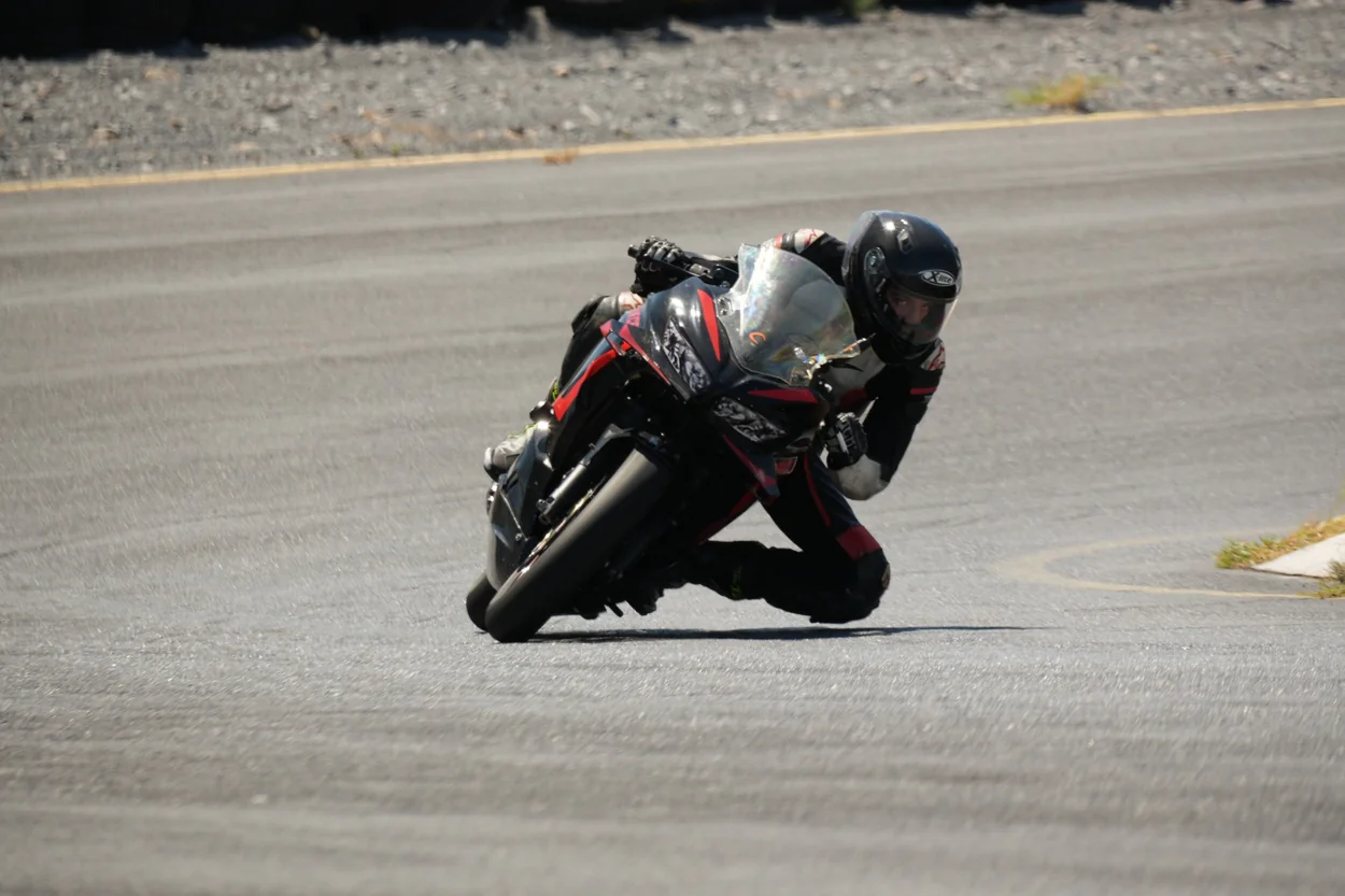 Piloto de moto negra y casco oscuro en circuito