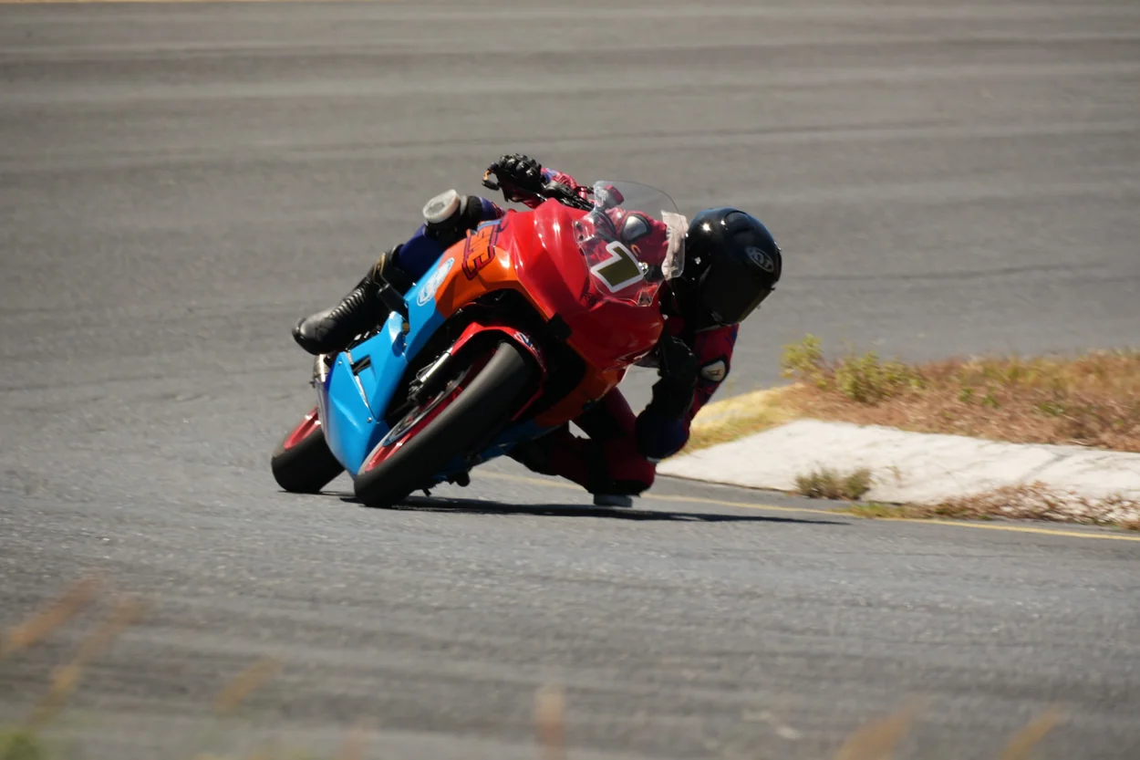 Piloto sobre motocicleta roja y azul tomando una curva
